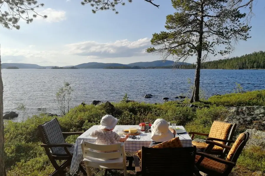 tisch mit personen, die gemütlich am see in der sonne sitzen