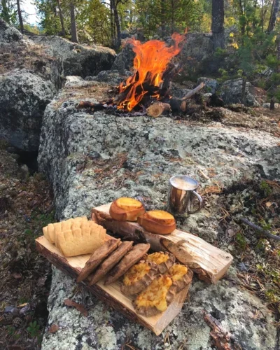 mahlzeit mit brot und kaffee auf einem stein am feuer